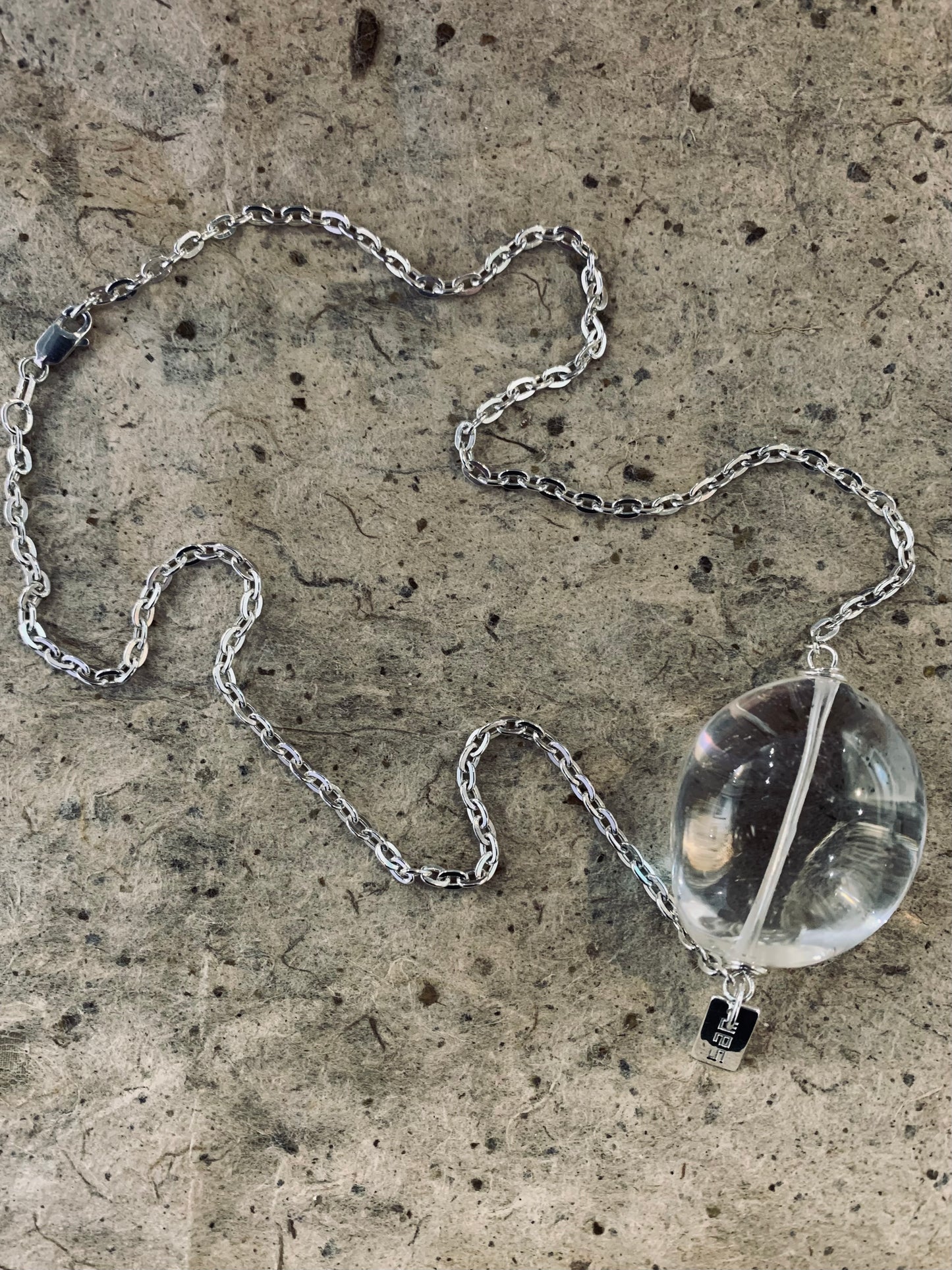 Clear quartz from Brazil carved into a smooth round pendant and set with a heavy sterling silver chain 