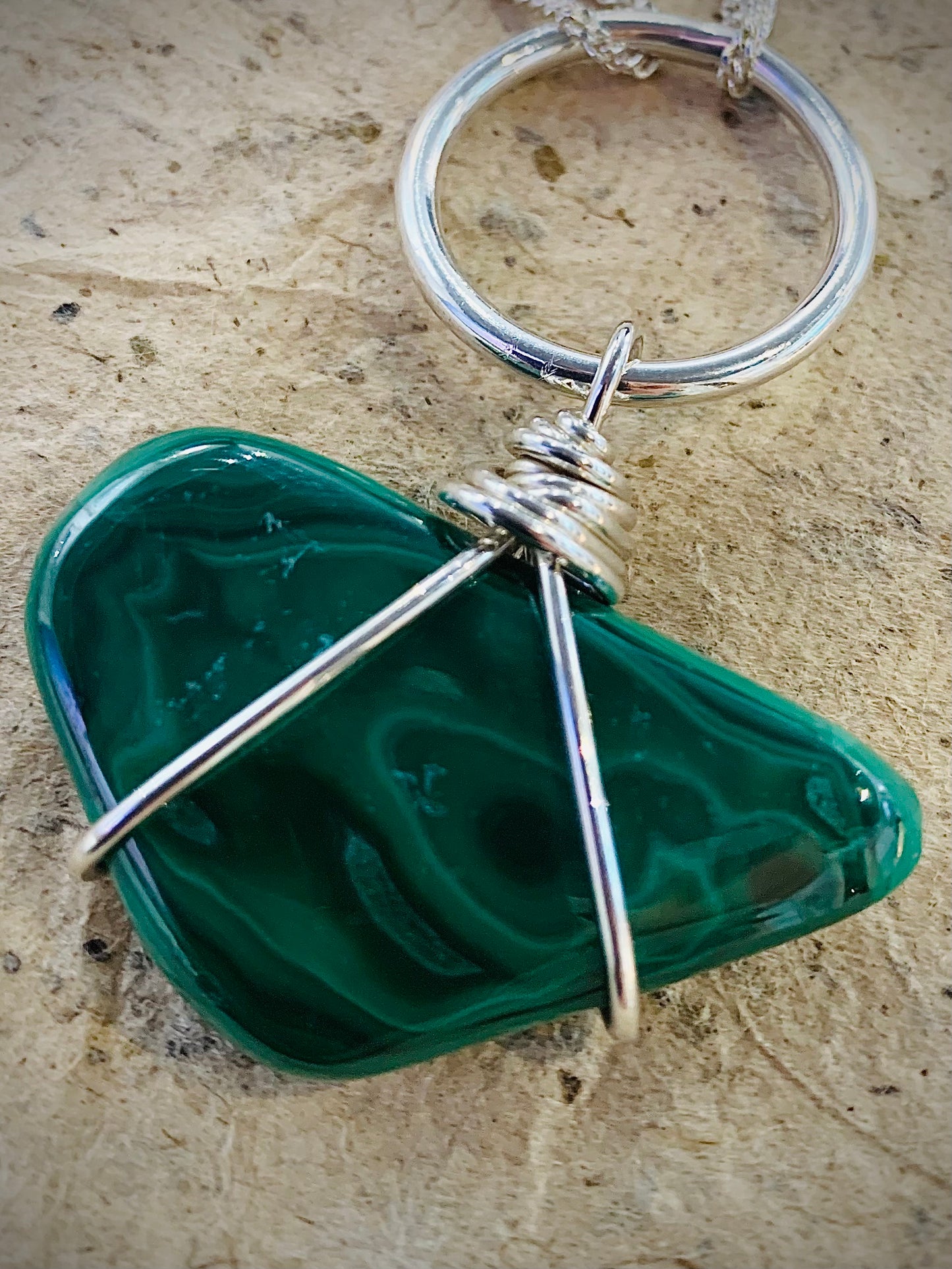 Close up image of an emerald green malachite pebble style pendant 