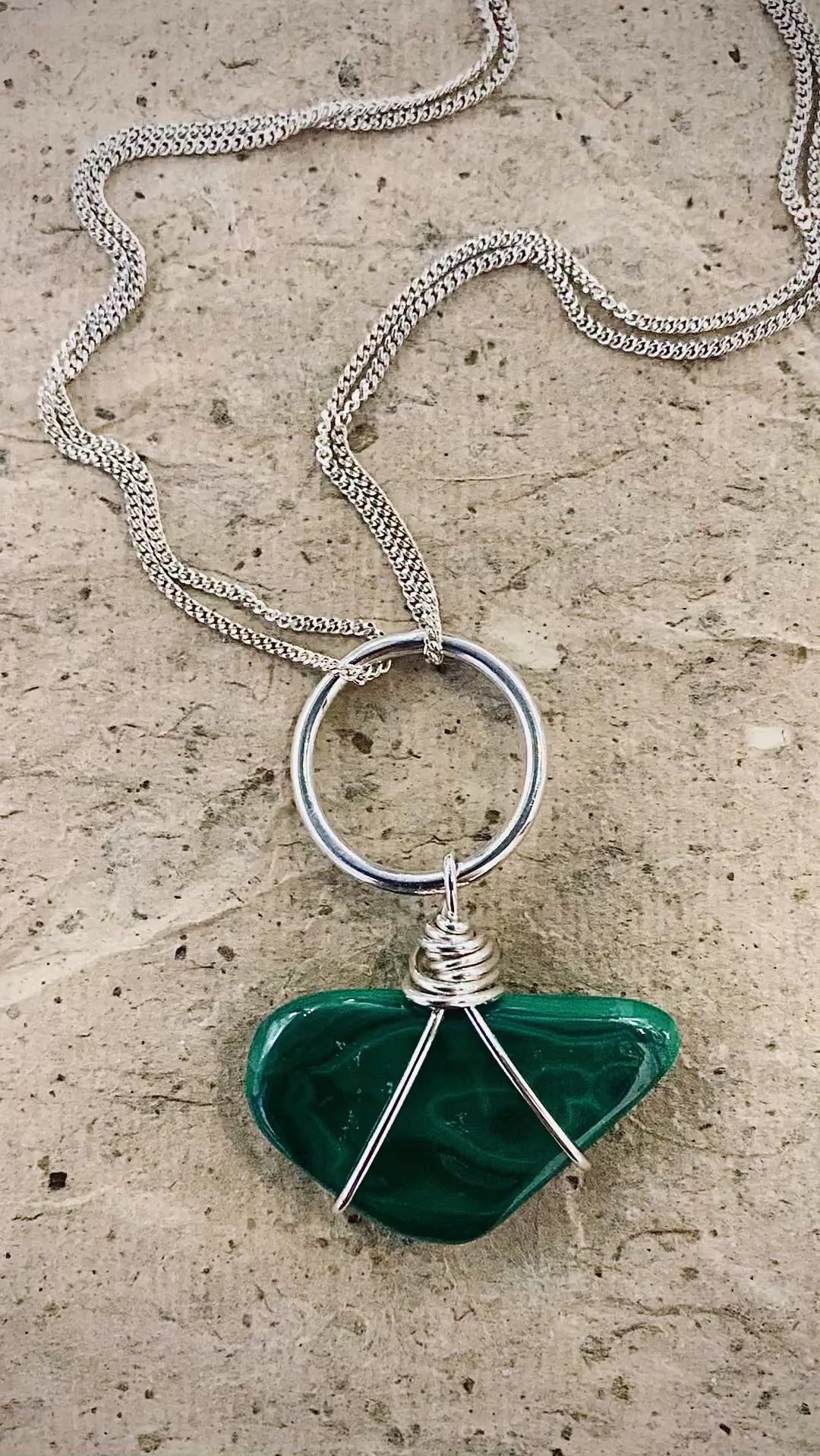 A video showing the natural contours of a large tumble’s slab of malachite set in sterling silver featuring double chains and a hand beaten silver setting 